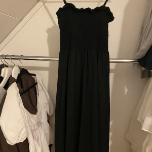 Svart klänning från H&M - Snygg svart lång klänning med axelband från H&M med smockdetaljer upptill🩷
