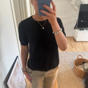 Svart kashmirtröja från Soft Goat - Säljer en elegant svart kashmirtröja från Soft Goat. Tröjan har korta ärmar och en rund halsringning, perfekt för en stilren look. Den är tillverkad i 100% kashmir vilket gör den otroligt mjuk och bekväm att bära.