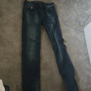 Mörkblå jeansbyxor - Snygga mörkblå jeans med en slim passform. De har en klassisk femficksdesign och en knappgylf. Perfekta för en stilren look.
