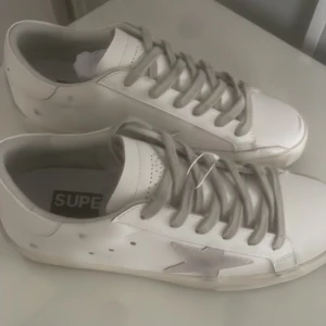 Vita sneakers med stjärndetalj - Snygga vita sneakers med en stjärndetalj på sidan. Skorna har snörning och en klassisk rund tå. Perfekta för en stilren och avslappnad look.