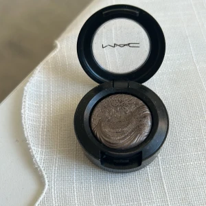 Silver Dawn Extra Dimension Ögonskugga från MAC - Snygg ögonskugga från MAC i nyansen Silver Dawn. Den har en skimrande finish och kommer i en praktisk rund dosa med genomskinligt lock. Perfekt för att skapa en glamorös look med djup och dimension.