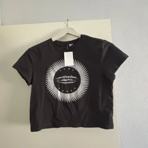Mörk grå t-shirt med tryck - Snygg mörkgrå  t-shirt med ett coolt tryck i vitt och grått på framsidan. Perfekt för en avslappnad stil. Kortärmad och i en bekväm passform. Helt ny