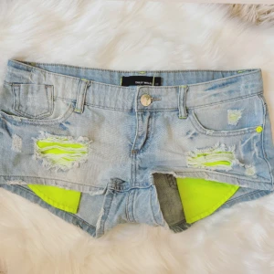 Mega lowrise super Lågmidjade ljusblåa jeanshorts med neon fickor - Såååå snygga! Midja rakt över: ca 40 cm