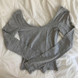 Grå långärmad topp Gina Tricot - Supersnygg grå långärmad topp från Gina Tricot med djup urringning i ryggen. Tunn och mjuk i materialet. Aldrig använd. 