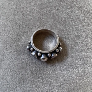 Silverring KumKum med pärla & stenar - Unik silverring från KumKum i 925 silver med cool design. Ringen har en rund pärla i mitten och flera gnistrande stenar runt om, dekorerad med små silverkulor. Perfekt statement piece för dig som gillar smycken som sticker ut.