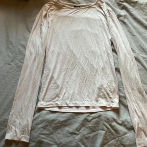 Ljusrosa långärmad basic tröja - Enkel och stilren ljusrosa långärmad tröja i mjukt bomullsmaterial. Perfekt att ha som basplagg och funkar till många olika outfits. Tröjan har rund halsringning och en rak passform.