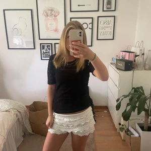 Svart spetsblus med kort ärm - Supersnygg svart blus i spets med korta ärmar och rund hals. Blusen har ett vackert spetsmönster över hela och en liten öppning med knapp i nacken. Perfekt att styla med kjol eller jeans för en trendig look. Storlek M men passar mig som har S🤗