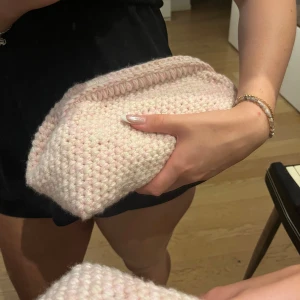 Handgjord ljusrosa stickad kuvertväska - Supersöt handgjord kuvertväska i ljusrosa, grovt stickat garn. Väskan har en mjuk och chunky känsla, perfekt att bära i handen. Enkel design utan synliga detaljer eller mönster, vilket gör den lätt att matcha med olika outfits. Kan också amdvändas som nessesär