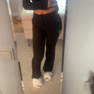 Svarta bootcut byxor med hög midja - Säljer ett par svarta bootcut byxor med medelhög midja och dragkedja fram. Byxorna har en snygg, figurnära passform upptill och lätt utsvängda ben. Perfekta att styla med crop top eller hoodie. Materialet känns mjukt och stretchigt.