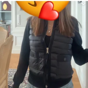 Svart cardigan jacka från Moncler - Snygg svart cardigan jacka från Moncler med quiltad framsida och två fickor med knapp. Jackan har dragkedja och Moncler-logga på ärmen. Perfekt för dig som vill ha en stilren och sportig look.