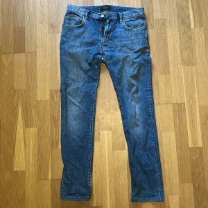 Blå jeans från J.Lindeberg - Klassiska blå jeans från J.Lindeberg med fem fickor och snygga kontrastsömmar. Jeansen har normal passform och raka ben, tillverkade i slitstarkt bomullsjeans. Perfekta för dig som gillar en tidlös look med en modern touch.