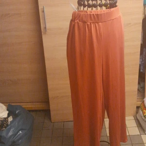 Vida orange byxor med resårmidja - Snygga vida byxor i en härlig orange färg med resår i midjan för extra komfort. Perfekta för dig som gillar en avslappnad och trendig stil. Lätta och luftiga, passar bra till både sneakers och sandaler.