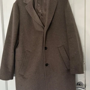 Brun rock från H&M No1 Essentials - En rock i filtad ullblandning med raffinerad twillstruktur som har en mjuk känsla och är extra stadig. Rocken är rent skuren med modern enkelknäppning och ledig passform. 