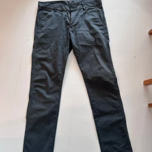 Mörkgrå chinos från Paul & friends - Snygga mörkgrå chinos från Paul & friends i klassisk rak modell. Byxorna har diskreta sidfickor, hällor för bälte och är tillverkade i bomull med lite stretch för extra komfort. Perfekta för en clean och stilren look.