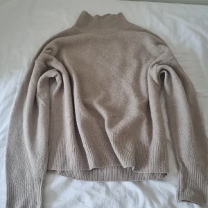 Stickad trjöja - Mysig beige polotröja från Gina Tricot i storlek XS. Tröjan är stickad med ribbade muddar och hög krage, perfekt för kyliga dagar. Enkel och stilren modell som är lätt att matcha med jeans eller kjol.