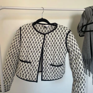 Jacka från hm 💕 - Quiltad overshirt i vitt med svart mönster och svarta kanter. Jackan har rund hals, knappar framtill och två fickor. Perfekt för lager-på-lager och ger en cool, avslappnad vibe till din outfit. Aldrig använd då jag köpt i fel storlek 💕