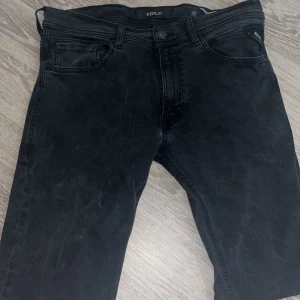 Svarta Replay Jondrill jeans herr - Säljer ett par svarta Replay i modellen Jondrill jeans i slim fit. Jeansen har klassisk femficksdesign, snygga svarta sömmar och Replay-logga på bakfickan. Modellen är smal och sitter tajt längs benen. Perfekta för dig som gillar en stilren och modern look. Kan sänka priset vid snabb affär.                                                                         TAR EMOT BYTEN