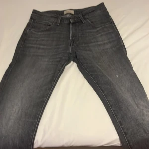 Grå Jack & Jones i storlek W28:L30 - Säljer ett par grå Jack & Jones i klassisk femficksmodell. Jeansen har en snygg tvättad look och raka ben. Passar dig som gillar en stilren och enkel vibe. Materialet är jeans och färgen är mörkgrå. Perfekta till sneakers eller boots.