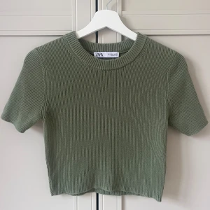 Ribbad topp från Zara - Grön ribbad topp från Zara med korta ärmar och croppad passform. Endast använd 1 gång!