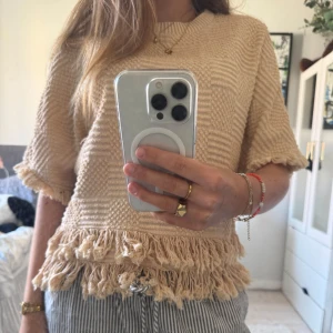 Beige stickad tröja med fransar - så snygg tröja som är härlig coh snygg att ha utomlands. Aldrig använd, perfekt för sommaren!
