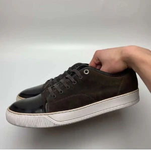 Bruna sneakers från Lanvin i mocka - Snygga bruna sneakers från Lanvin med ovandel i mocka och lackad svart tå. Skorna har vita gummisulor och klassisk snörning. Perfekta för dig som gillar stilrena och exklusiva sneakers med en twist.