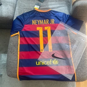 FC Barcelona Neymar JR 2015 matchtröja - Säljer en äkta FC Barcelona Neymar JR 11 matchtröja från säsongen 2015/16. Tröjan är kortärmad, tillverkad i lätt och ventilerande polyester. Klassiska blå och röda breda ränder, gula detaljer och klubbmärke på bröstet. Nike-logga, Qatar Airways och UNICEF-tryck.