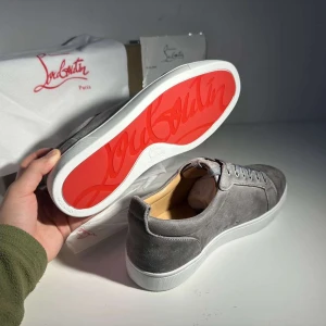 Christian Louboutin Skor - Snygga grå sneakers från Christian Louboutin i mjuk mocka med klassisk röd sula och vita kanter. Skorna har rund tå, snörning och diskreta detaljer. Perfekta för dig som vill sticka ut med exklusiv streetstyle.