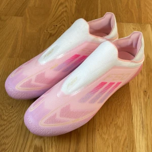  F50 rosa fotbollsskor - Säljer ett par F50 fotbollsskor i en snygg rosa och vit färgkombination. Skorna har en strömlinjeformad design utan snörning. Perfekta för dig som vill sticka ut med stil. De var för små så jag har inte kunnat använda dom pris kan diskuteras!