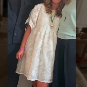 Vit broderad kortklänning med knytärmar från other stories - Supersöt vit kortklänning från other stories med broderade detaljer och voluminösa ärmar med knytband. Klänningen har en lös passform och rund halsringning. Perfekt för sommarens alla tillfällen!