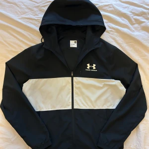 Svart och vit vindjacka från Under Armour - Säljer en jätte snygg vind jacka från Under Armour. Den har inga defekter. Storlek M. Den perfekta jackan nu fram till sommaren men också sommar kväll. Skriv om ni har frågor