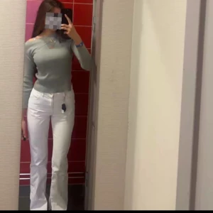 Vita jeans - Säljer ett par vita bootcut jeansbyxor med normal passform och hög midja. Byxorna har klassisk femficksdesign och stängs med dragkedja och knapp. Perfekta för dig som vill ha en fräsch och stilren look.