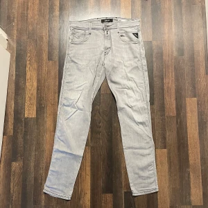Ljusgråa jeansbyxor från Replay Anbass - Säljer ett par ljusgråa Replay Anbass jeans med slim fit. Klassisk femficksmodell med dragkedjegylf och diskreta detaljer. Perfekta för dig som gillar en smalare passform och stilren look.