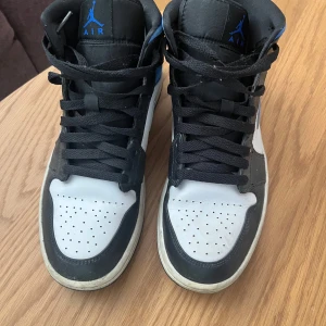 Nike Air Jordan 1 Mid svart, vit och blå -  Tjena säljer ett par Nike Air Jordan 1 Mid i storlek 43 passar även dem som har storlek 42.  Nypris är 2500 men jag säljer för 350kr. Du får även med creaseskydd hare bra.