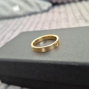 Stol guld ring  - Snygg stol guld ring med en infattad klar sten och dekorativa hjärtor runt om. Perfekt accessoar för att lyfta din stil.