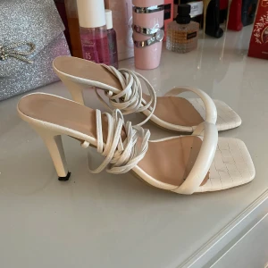 Vita klackade sandaler med snörning - Säljer ett par vita sandaler med klack och fyrkantig tå. Skorna har flätad detalj framtill och långa snören som kan lindas runt vristen. Använda fåtal gånger🤍