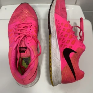 Nike Pegasus 33 löparskor i neonrosa - Säljer ett par Nike Pegasus 33 löparskor i en riktigt snygg neonrosa färg med svarta detaljer och vit sula. Skorna har ventilerande meshmaterial och klassisk snörning. Perfekta för dig som vill sticka ut på löprundan!