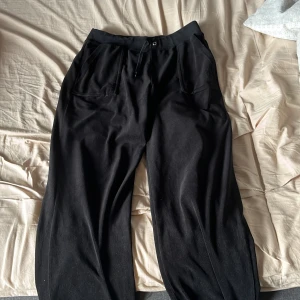 Svarta mjukisbyxor från Juicy Couture - Svarta mjukisbyxor från Juicy Couture med broderad JC-logga vid benet. Köpte 2022 men använda ungefär 3 gånger och inte användt sedan dess, väldigt sköna och är i storlek M. Säljer för 300 men kan diskuteras till 260kr. Köpta för 1100