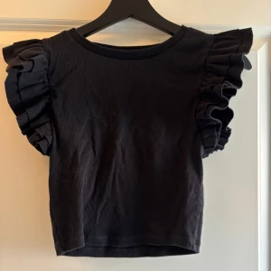 Svart topp med volangärmar - Säljer en svart topp med korta, stora volangärmar från Zara