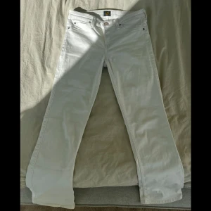 Vita bootcut jeans från Lee - Ett par skitsnygga vita lågmidjade Levi’s jeans. Utsvängda jeans. Storlek: W28 L33. Bra skick, har slitningar på baksida vid änden. I och med att byxorna är en längre modell finns möjlighet att sy upp/klippa den smutsiga kanten. Dessa säljs inte längre.