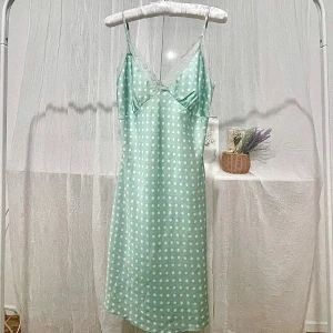 Mintgrön prickig klänning med spetsdetaljer - Säljer en mintgrön klänning med vita prickar och tunna axelband. Den har tyvärr fläck vid bröstet (se sista bild). Gratis vid köp av en annan plagg, bara säga till efter att du har gjort ett köp! 