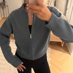 Blå stickad bomberjacka från Zara - Säljer en blå stickad bomberjacka från Zara med dragkedja framtill. Modellen är croppad med ribbade muddar vid ärmslut och nederkant.💓💓 Aldrig använd, i barn storlek men passar mig jättefint. jag är 163💓