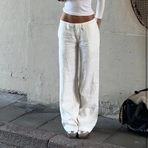 Alobha linnebnyxor  - Säljer ett par fräscha uppsydda vita linnebyxor med normal passform och raka ben. Byxorna har hög midja och stängs med dragkedja och knapp framtill. Perfekta för en stilren och luftig look. 