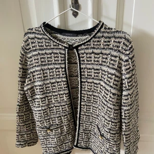 Svart vit kofta - Säljer en helt oanvänd beige/svart/vit kofta med guld detaljer! Koftan går att knäppa längst upp (se bild) men snygg att ha öppen också! Skriv privat för bild på ⭐️😇Står ingen storlek men passar S/M skulle jag säga!