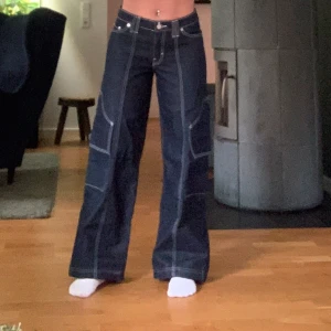 Mörkblå wide jeans från Weekday - Säljer ett par super coola mörkblå jeans från Weekday med kontrastsömmar och breda ben. Byxorna har låg midja och coola detaljer med vita sömmar längs benen. Dem är lite uppsydda som man kan se på sist bilden. Det är professionellt gjort. Men självklart går det att ta bort de om man vill det. Jag är 158cm lång och dem passar helt perfekt på mig! Köpta för 900kr. Jag har aldrig använt dem endast testat hemma. Bara att skriva vid frågor! Priset är diskuteringsbart.