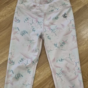 Blommiga träningsleggings  från Iconic - Säljer ett par ljusa träningsleggings från Iconic med blommigt mönster.