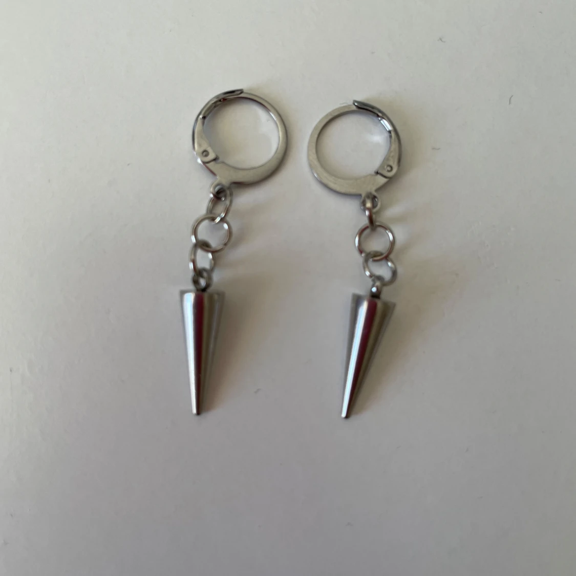 Silvriga örhängen med konformad hängande detalj