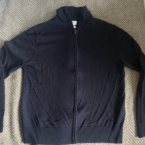 These Glory Days full zip tröja mörkblå  100% merinoull  - Mörkblå full zip-tröja från These Glory Days i 100% merinoull – mjuk, värmereglerande och stilren. Storlek M, men den är något krympt och passar nu bättre som en S. I bra använt skick utan hål eller fläckar. Perfekt som lager på lager-plagg eller som ett mer uppklätt alternativ till hoodie eller kofta.