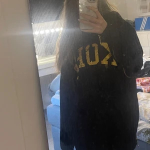 Svart hoodie från Michael Kors med gulddetaljer - Säljer en svart hoodie från Michael Kors med stora guldfärgade bokstäver på bröstet. Tröjan har huva, magficka och en snygg dragkedja längs sidorna. Tröjan är använd ett fårtal gånger och har inga defekter😊💕pris går alltid att diskutera!