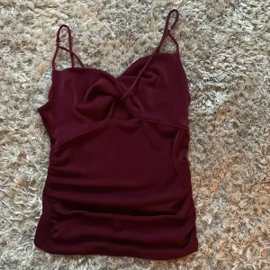 Vinröd linnetopp - Säljer en vinröd linnetopp med smala axelband och snygg twistad detalj framtill. Toppen har en liten cut-out under bysten och är figurnära i modellen. ⭐️