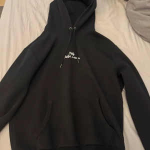 Svart hoodie från Polo Ralph Lauren - Svart hoodie från Polo Ralph Lauren med broderad vit logga på bröstet. Klassisk känguruficka framtill och justerbar huva med snören.